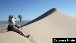 Seorang teknisi suara memasang peralatannya untuk merekam "nyanyian" bukit pasir di Gurun Mohave, California. (Foto: Trevor Cox)