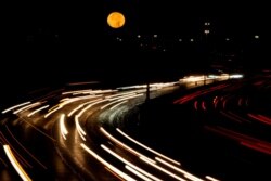 The full moon sets as morning traffic travels on a freeway Thursday, Oct. 1, 2020, in Leawood, Kan. (AP Photo/Charlie Riedel)