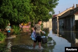 Stanovnici Nove Kahovke prenose lične stvari posle poplave izazvane probijanjem brane (Foto: Reuters)