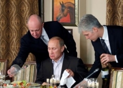 FILE - Evgeny Prigozhin (L) assists then-Russian Prime Minister Vladimir Putin during a dinner at Cheval Blanc restaurant on the premises of an equestrian complex outside Moscow, Russia, Nov. 11, 2011.