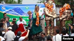 Amelia Rose Hillary (C) walks to place a garland on statues of her grandfather Sir Edmund Hillary (L) and Tenzing Norgay Sherpa (R), in Kathmandu, May 29, 2013.