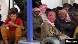 FILE - Syrian refugees wait to board a Jordanian army vehicle after crossing into Jordanian territory with their families, in al-Ruqban border area, near the northeastern Jordanian border with Syria, and Iraq, near the town of Ruwaished, 240 km (149 miles) east of Amman, Sept. 10, 2015.