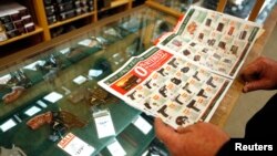 FILE - A customer looks through the in-store sales advertisements inside a store that sells guns in Texas. 