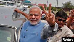 Hindu nationalist Narendra Modi, the prime ministerial candidate for India's Bharatiya Janata Party (BJP), gestures towards his supporters from his car during a road show upon his arrival at the airport in New Delhi, May 17, 2014.