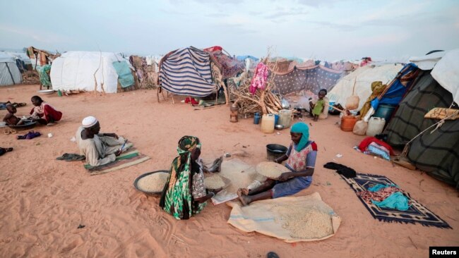 FILE - Fatouma Abubakr, 70, who fled the conflict in Sudan's Darfur region, sits with her daughter outside their makeshift shelter in Adre, Chad, Aug. 5, 2023.