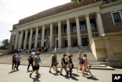 People walked past the entrance to the Widener Library, behind, on the Harvard University campus in Cambridge.  (Photo: AP)