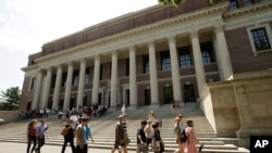 FILE - People walk past an entrance to Widener Library on the campus of Harvard University, in Cambridge, Mass., July 16, 2019.