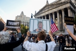 Demonstran anti-Trump memegang poster terkait kasus penipuan perdata yang diajukan oleh Jaksa Agung negara bagian Letitia James, di New York City, AS, 2 Oktober 2023. (Foto: REUTERS/Caitlin Ochs)