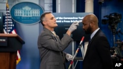 A member of the White House physicians office checks temperatures prior to a press briefing with the coronavirus task force, at the White House, March 16, 2020.
