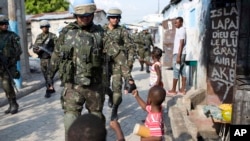 des soldats de la paix du Brésil saluent des enfants en patrouillant dans le bidonville de Cité Soleil, à Port-au-Prince, Haïti, 22 février 2017. 