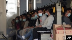 Migrantes con máscaras faciales y grilletes en manos y pies sentados en un avión militar en Fort Bliss en El Paso, Texas, el 30 de enero de 2025, esperando su deportación a Guatemala. 