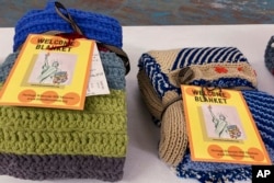 Handmade blankets for refugees sit on a table at a Welcome Blanket giveaway at the Association of Africans Living in Vermont, March 21, 2023, in Burlington, Vt. (AP Photo/Lisa Rathke)