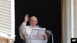 Paus Fransiskus melambaikan tangan ke arah kerumunan umat dari jendela ruang kerjanya untuk misa siang hari, di Vatikan. 