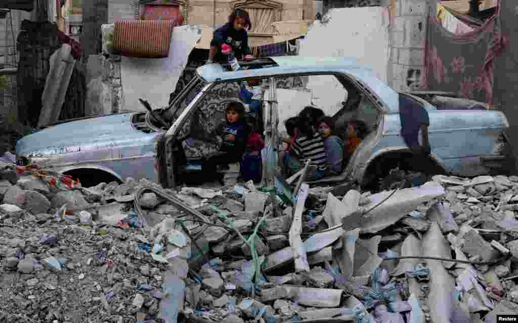 Palestinian children gather at a destroyed vehicle in Khan Younis in the southern Gaza Strip amid the Israel-Hamas conflict.