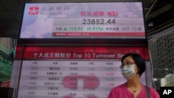 A woman wearing face mask walks past a bank electronic board showing the Hong Kong share index at Hong Kong Stock Exchange Tuesday, June 2, 2020. Shares were mostly higher in Asia on Tuesday, lifted by moves to reopen many regional economies from…