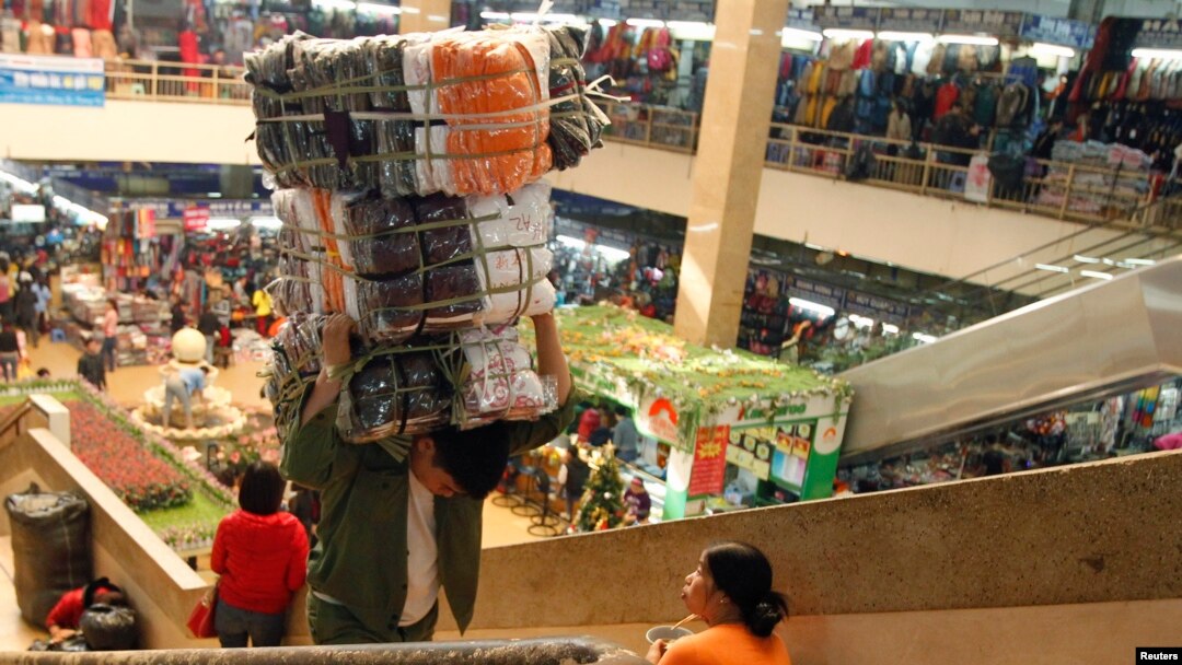 FILE - A man carries a bag of clothes at Dong Xuan market in Hanoi, Dec. 21, 2012. Vietnam is estimated to have a trade deficit of $200 million in December, while its annual trade balance will be at a surplus of $284 million, a state-run newspaper reported.