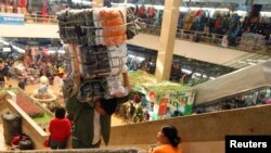 FILE - A man carries a bag of clothes at Dong Xuan market in Hanoi, Dec. 21, 2012. Vietnam is estimated to have a trade deficit of $200 million in December, while its annual trade balance will be at a surplus of $284 million, a state-run newspaper reported.