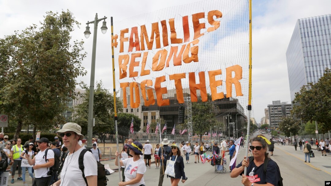 FILE - Demonstrators hold signs as they participate in the "Families Belong Together: Freedom for Immigrants" march in Los Angeles, June 30, 2018. 