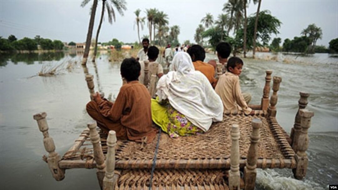 Penduduk desa Pakistan menyeberangi banjir di daerah Baseera, Pakistan, 24 Agustus 2010.