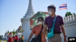 Dua wisatawan mengenakan masker saat mengunjungi Istana Raja di Bangkok, Thailand hari Senin (27/1). 