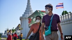 People walk with face masks outside the Grand Palace in Bangkok on January 27, 2020. - Thailand has detected eight Coronavirus cases so far -- three of whom are receiving treatment in hospital and five of whom have been discharged, according to a statemen