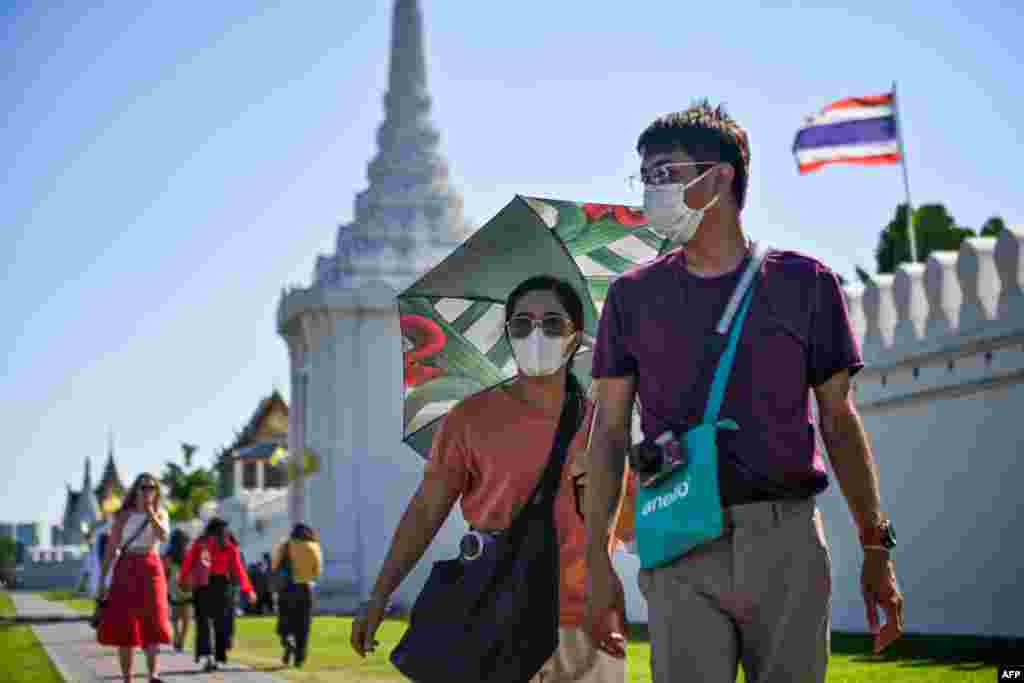 Dua orang wisatawan mengenakan masker saat mengunjungi Istana Raja di Bangkok, Thailand di tengah merebaknya virus corona di berbagai negara.&nbsp;