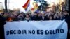 The president of Catalonian Parliament, Roger Torrent, center, and the Catalan regional President Quim Torra, center right, hold a placard that reads in Spanish: " To Choose is not a Crime", outside the Spanish Supreme Court in Madrid, Feb. 12, 2019.