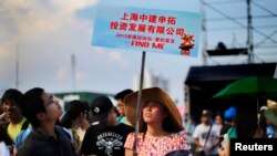 Seorang perempuan memegang papan dalam acara pencarian jodoh di pantai Jinshan, selatan Shanghai (20/7).