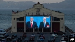 People watch from their vehicles as President Donald Trump, on left of video screen, and Democratic presidential candidate former Vice President Joe Biden speak during a Presidential Debate Watch Party at Fort Mason Center in San Francisco, Thursday…
