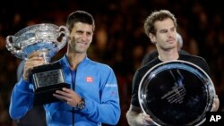 Petenis Serbia Novak Djokovic, kiri, memegang piala bersama petenis Skotlandia Andy Murray setelah memenangkan kejuaraan tenis Australia Terbuka di Melbourne, Australia, 1 Februari 2015. 