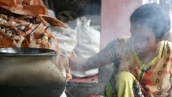 Smoke rises as an Indian woman cooks a mid-day meal on a traditional oven in Calcutta in 2007