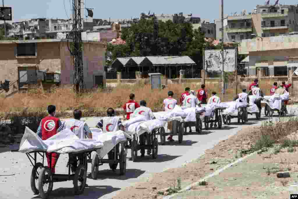 Members of the Syrian Red Crescent transport the bodies of reported regime fighters from rebel-held area into regime-held area through the Garage al-Hajz crossing in the Bustan al-Qasr district of the northern Syrian city of Aleppo during a reported exchange operation between the two sides.