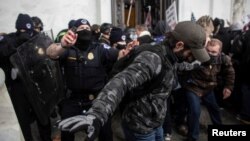 Сотрудники правоохранительных органов противостоят протестующим, штурмовавшим Капитолий 6 января 2021 г.