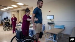 FILE - Israeli soldier Jonathan Ben Hamou, 22,wounded in the war with Hamas, practices standing during a physiotherapy session in Sheba Hospital's rehabilitation division in Ramat Gan, Israel, Monday, Dec. 18, 2023.