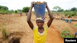 Une femme cherche de l'or après la découverte d'une nouvelle mine trouvée dans une ferme de cacao près de la ville de Bouafle, dans l'ouest de la Côte d'Ivoire, le 20 mars 2014.