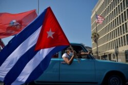 FILE - Cubans drive past the U.S. Embassy during a rally calling for the end of the U.S. blockade against Cuba, in Havana, March 28, 2021