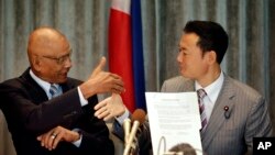 Philippine Congressman Rodolfo Biazon, left, Chair of the House Committee on National Defense, and Hiroshi Nakada, Head of delegation of the Japanese opposition Party for Future Generations, shake hands shortly after signing a non-binding documents to rea