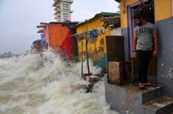 An Indian man arrives to sell umbrellas at a slum on the Arabian sea shore in Mumbai, India, Wednesday, July 3, 2019.