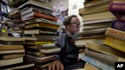 FILE - Geoff Klass works on a computer in his bookstore containing some 2 million books and prints in Johannesburg, Feb. 8, 2016. The Collectors Treasury is dedicated to preserving history and nostalgia. 