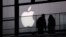 FILE - People walk past the Apple logo near an Apple Store at a shopping area in central Beijing, February 19, 2013