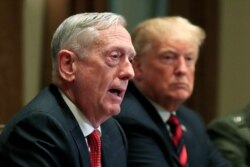 FILE - Then-Defense Secretary Jim Mattis speaks beside President Donald Trump during a briefing in the Cabinet Room at the White House in Washington, Oct. 23, 2018.