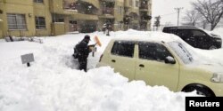 资料照：日本北海道地区北见市的一名男子从深雪中挖出汽车。（2022年12月24日）