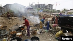 Women grills fish for sale at a slum area near railway tracks in Phnom Penh, Cambodia, Jan. 13, 2016.