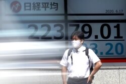 A man stands in front of an electronic stock board showing Japan's Nikkei 225 index at a securities firm as a vehicle goes by in Tokyo, June 17, 2020.