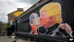 Un enfant marche le long d'un graffiti représentant Donald Trump et Vladimir Poutine s'embrasser, à Vilnius, Lithuanie, le 14 mai 2016. 