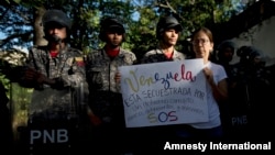 An opposition member holds a poster that reads in Spanish "Venezuela is kidnapped by a corrupt government, criminals and murderers" during a protest outside of the city's morgue in Caracas, Jan. 20, 2018.