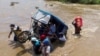 Un grupo de personas cargan un mototaxi por una corriente crecidas tras las lluvias provocadas por el ciclón Yaku en Piura, Perú, el 11 de marzo de 2023.