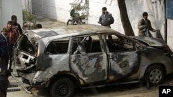 Police officers stand around an Israeli diplomat's car that was damaged in an explosion in New Delhi, India, February 14, 2012.