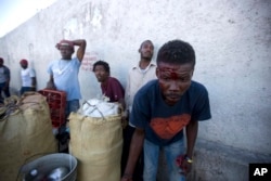 An injured man looks for help after gun shots rang out at the end of a ceremony marking the 212th anniversary of the assassination of independence hero Gen. Jean-Jacques Dessalines in Port-au-Prince, Haiti, Oct. 17, 2018.