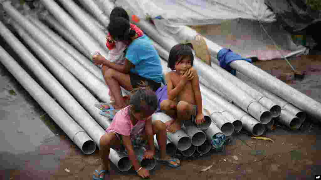 Filipinos sit on new lightposts as rain briefly stops in Makati, Philippines, Sept. 14, 2014. 